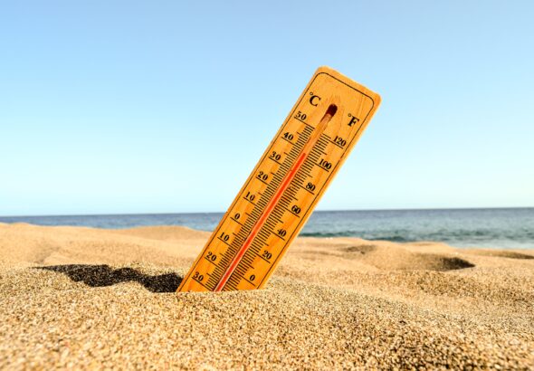 Selective focus shot of a thermometer in the beach sand with a blurred background